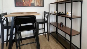 Un espace repas comprenant une table, des chaises, un tableau et une étagère avec divers objets.