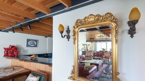Ein Zimmer mit Holzboden, einem großen, verzierten Spiegel und einem Essbereich, der sich im Spiegelbild zeigt.