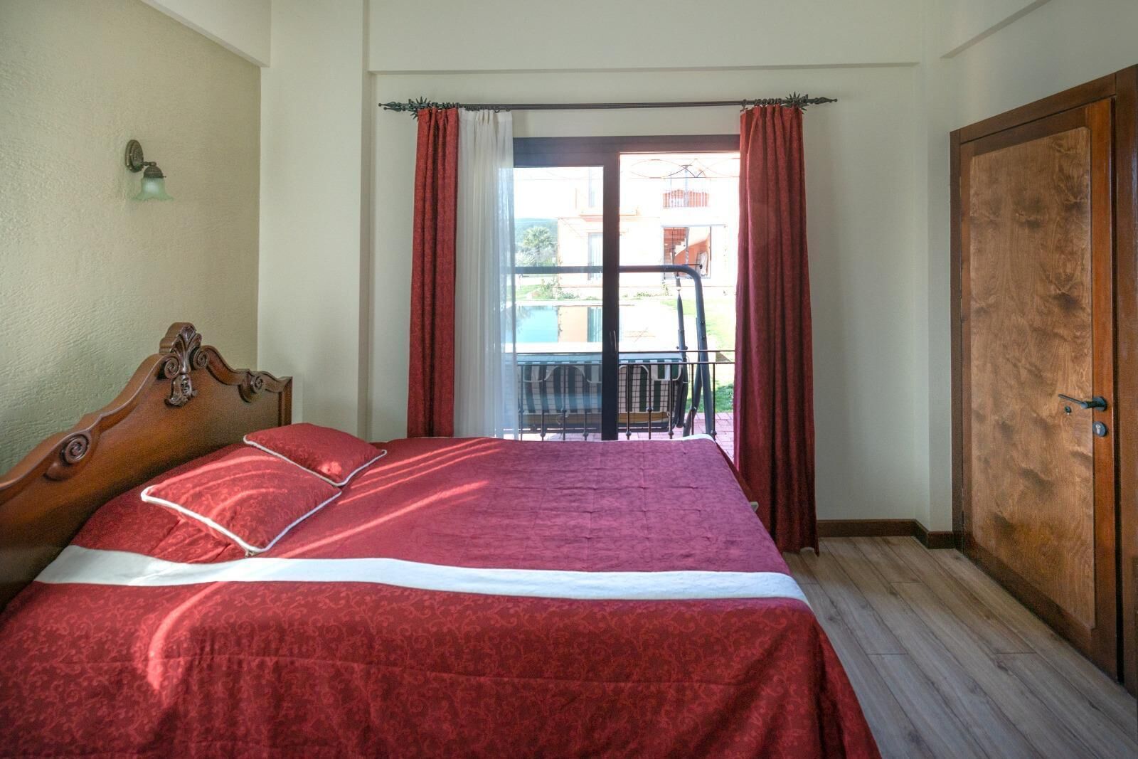Una camera da letto con un letto di legno, un balcone con una sedia e un armadio in legno.