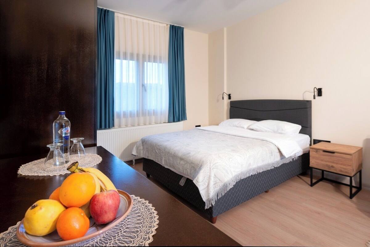 A hotel room with a bed, bedside table, and a fruit bowl.