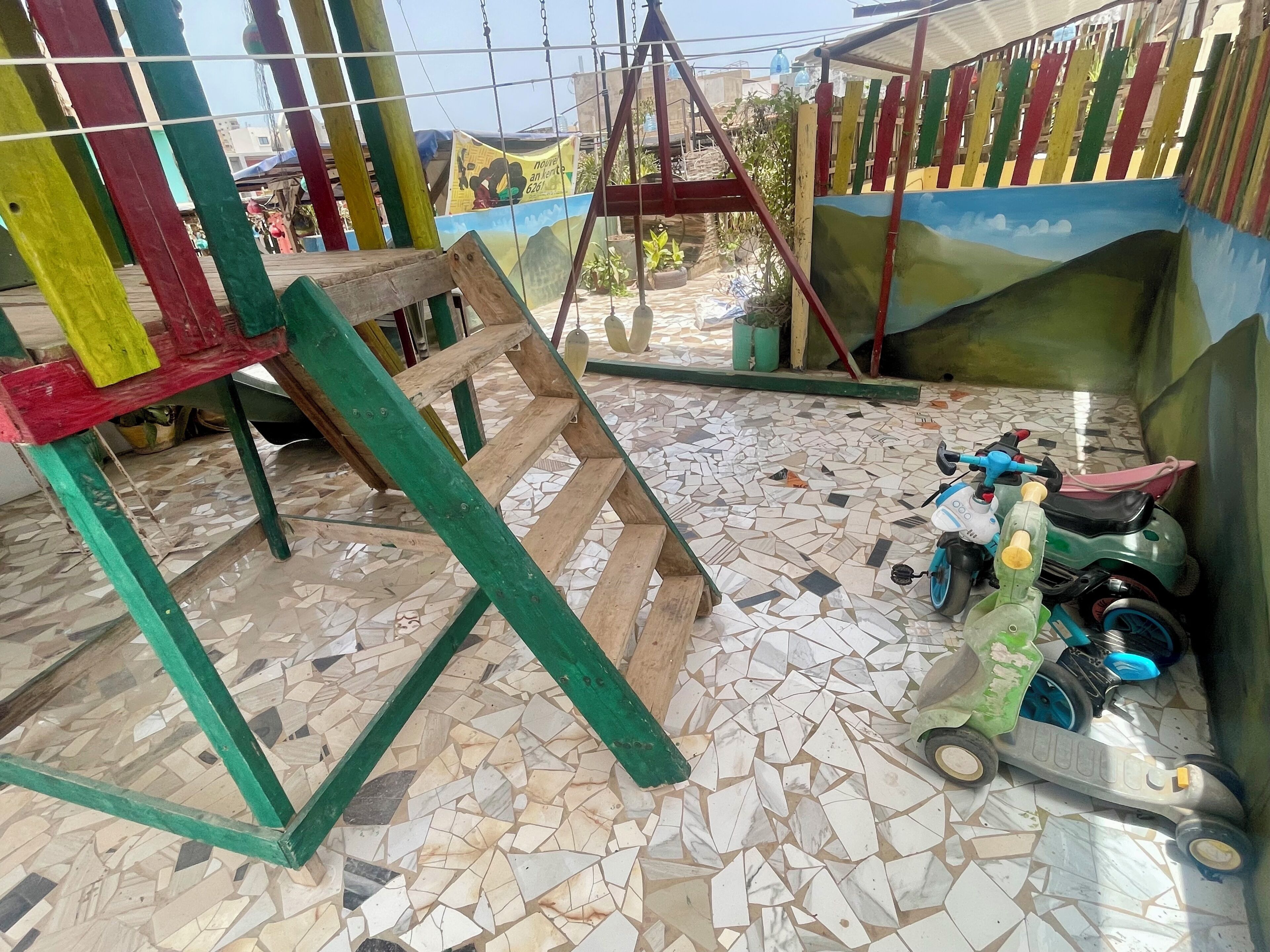 A room with a mosaic floor, a swing set, and a scooter.