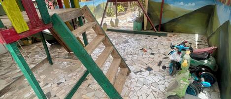 A room with a mosaic floor, a swing set, and a scooter.