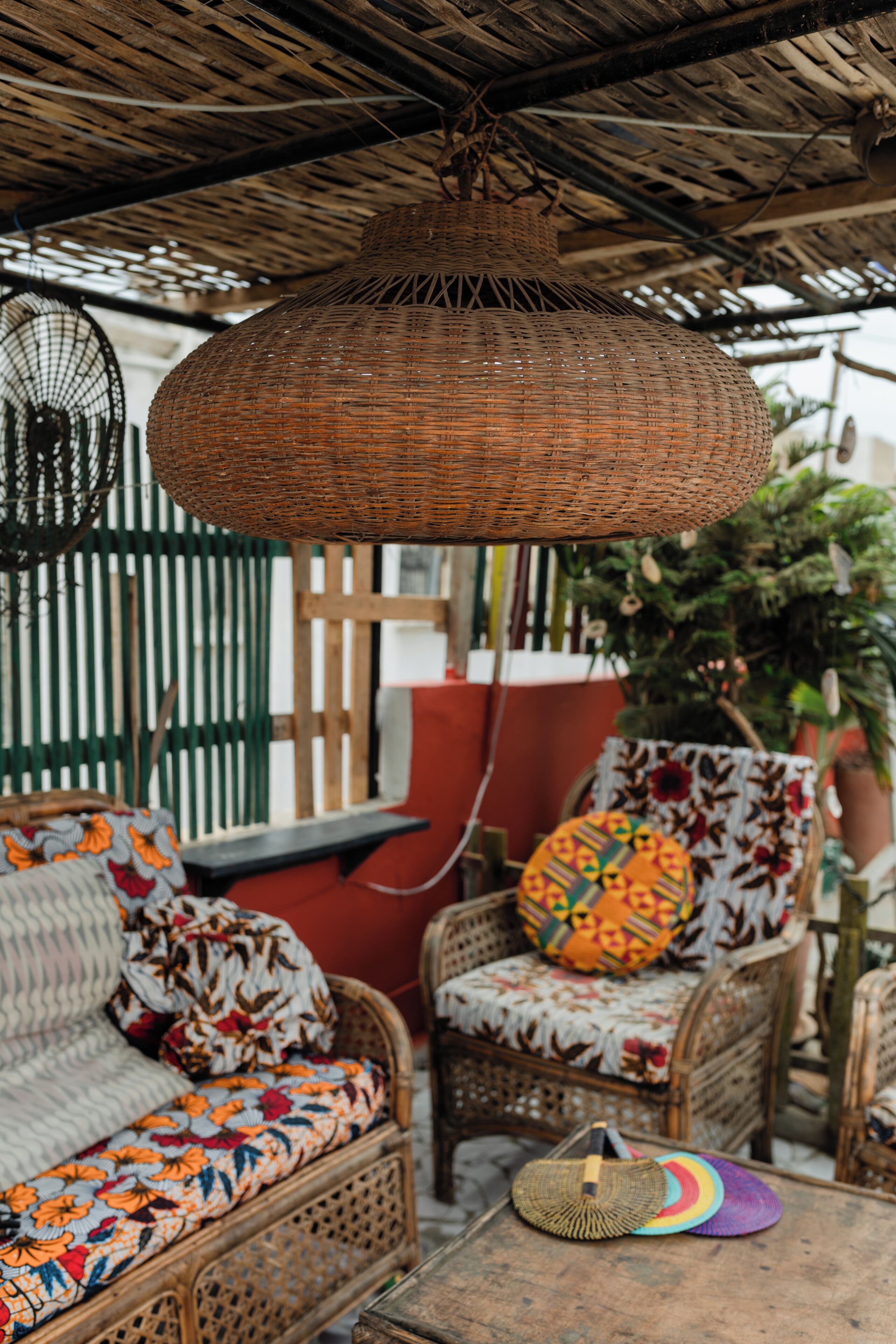 A wicker hanging light fixture, wicker furniture, and a table with a woven basket.