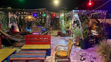 A cozy outdoor seating area with hammocks, colorful benches, and a mosaic-tiled floor.