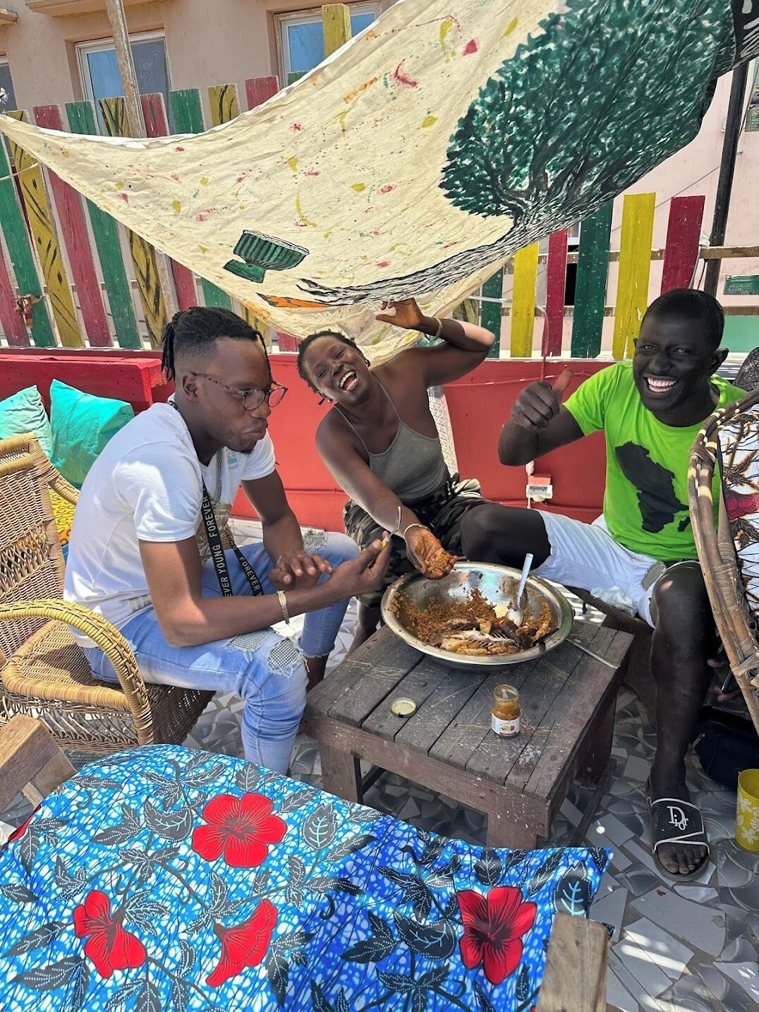 Un grupo de personas sentadas en una mesa de madera al aire libre, comiendo de un plato de metal.