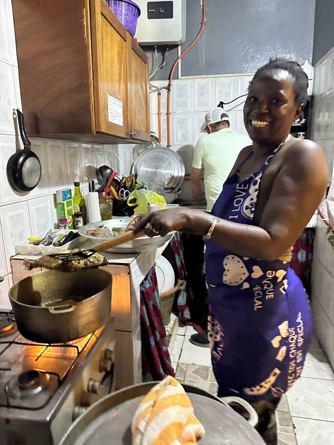 Una persona cocinando en una cocina con estufa a gas, ollas y diversos utensilios.