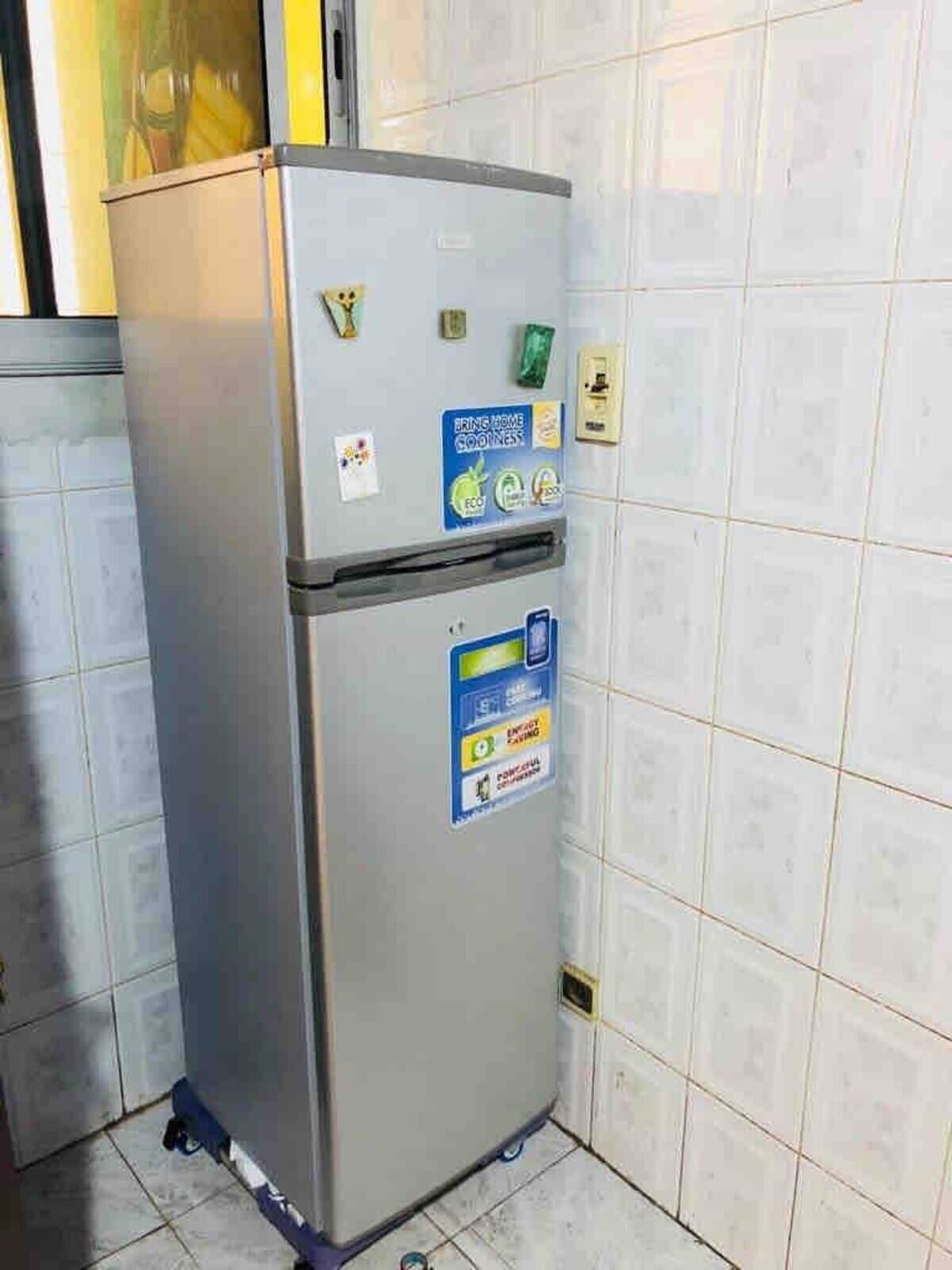 A compact, stainless steel refrigerator with multiple stickers indicating energy-saving features and recycling options.