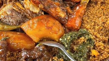 Una gran fuente de metal llena de diversos alimentos, como carne, verduras y granos.