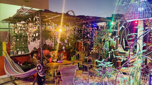 Een terras met rieten meubilair, een hangmat en decoratieve planten.