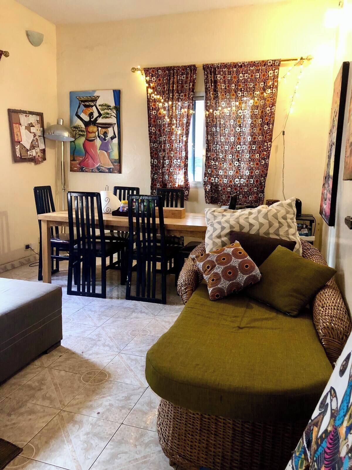 A cozy living room with a sofa, a dining table with chairs, and a painting on the wall.