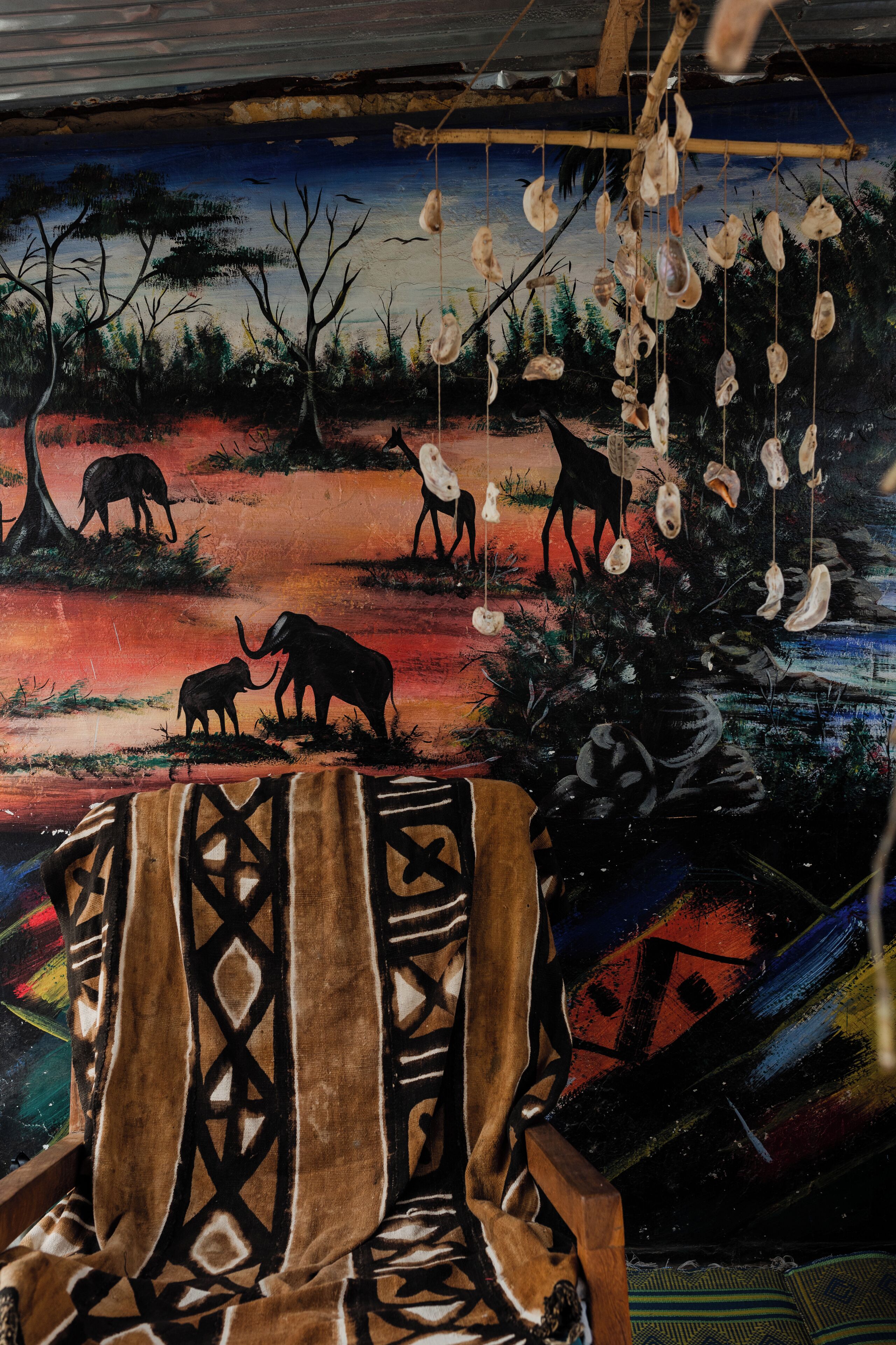 A room with a mural depicting wildlife and a hanging shell decoration.