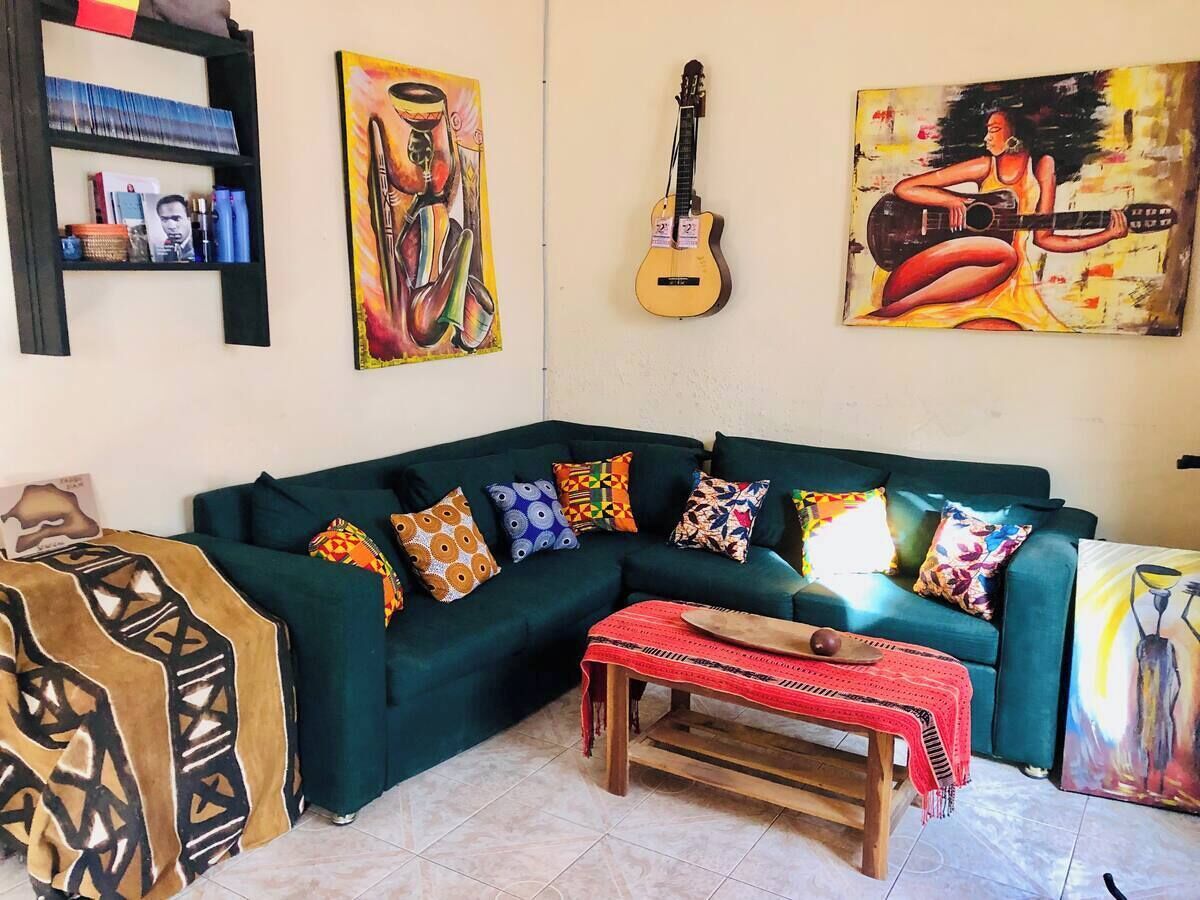 A living room with a green sofa, colorful cushions, a wooden coffee table, and paintings on the walls.