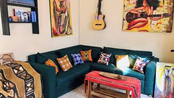 A living room with a green sofa, colorful cushions, a wooden coffee table, and paintings on the walls.