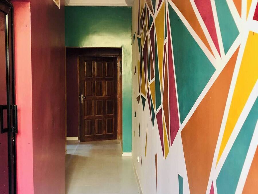 Un pasillo con un papel tapiz de diseño geométrico, una puerta de madera y un suelo de baldosas.