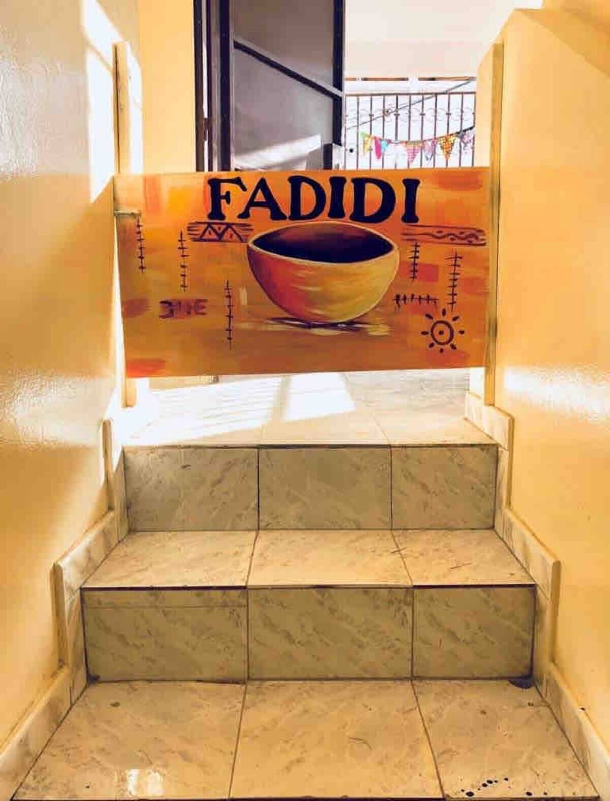 Una escalera que conduce a una habitación con un letrero que dice 'FADIDI' y un gráfico de un cuenco.