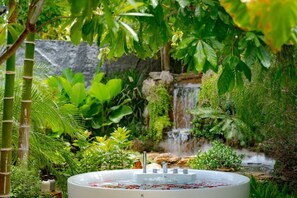 Un jacuzzi rodeado de abundante vegetación y una cascada.