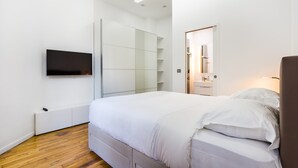 A modern bedroom with a bed, built-in wardrobe, and a TV mounted on the wall. - Peaceful Apartment - 1br/4p - Eiffel Tower (Paris)