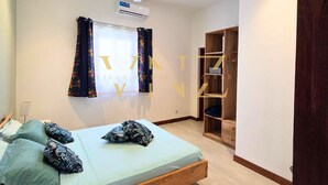 A bedroom with a bed, pillows, a ceiling fan, an air conditioning unit, and a wooden wardrobe. - Villa Nyota Eco Luxe (Jambiani)