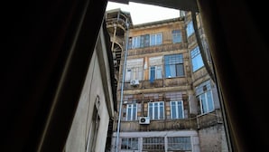Une vue à travers une fenêtre d’un immeuble à plusieurs étages, doté de balcons et de climatiseurs.