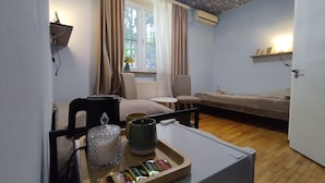 Une pièce confortable avec un lit, une chaise, une petite table sur laquelle se trouve un plateau de collations, un radiateur et une fenêtre avec des rideaux.