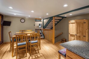 Ein Essbereich mit Holztisch und -stühlen, eine Treppe mit Holzgeländern sowie ein eingebauter Kleiderschrank.