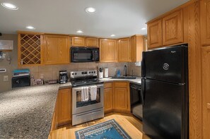 A kitchen with wooden cabinets, a black refrigerator, a microwave, a stove, and a dishwasher. - Alpine Adventure Lodge (Steamboat Springs)
