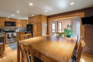 A kitchen with wooden cabinets, a microwave, stove, refrigerator, and a dining table with chairs. - Alpine Adventure Lodge (Steamboat Springs)