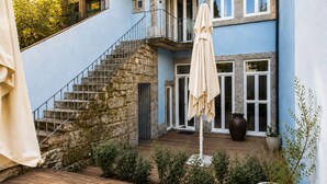 A blue building with a stone staircase, a wooden deck, and a potted plant.