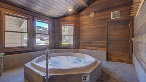 A hot tub in a wooden room with large windows and a door.