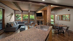 A modern kitchen with granite countertops, a dining area with a wooden table and chairs, and a built-in TV.