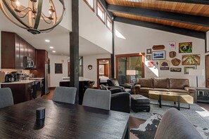 A spacious living area with a dining table, sofas, and a kitchen in the background.