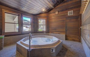 A wooden cabin interior with a hot tub, large windows, and a door. - Alpine Retreat Lodge (Steamboat Springs)