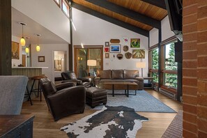A spacious living room with leather furniture, a large rug, and artwork on the walls.