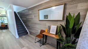A modern interior with a wooden staircase, a desk with a chair, and a large mirror on the wall.