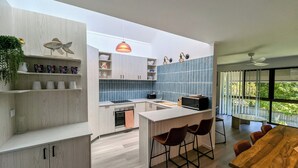 A modern kitchen with light wood cabinets, a central island, and bar stools.