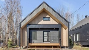 Ein modernes Haus mit Holzfassade, einer großen Haustür und einem kleinen Fenster darüber.