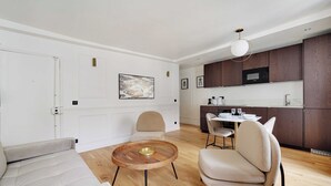 Ein modernes Wohnzimmer mit einer Couch, einem runden Couchtisch und einem Essbereich mit Tisch und Stühlen.