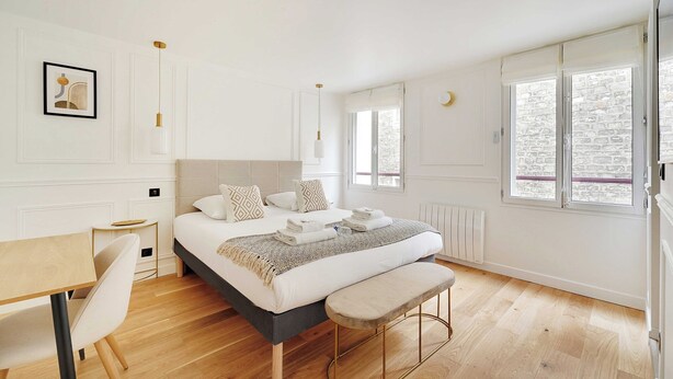 Ein modernes Schlafzimmer mit einem großen Bett, Nachttischen, einem Schreibtisch und einer Bank.