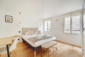 Une chambre moderne avec un grand lit, des tables de chevet, un bureau et un banc.