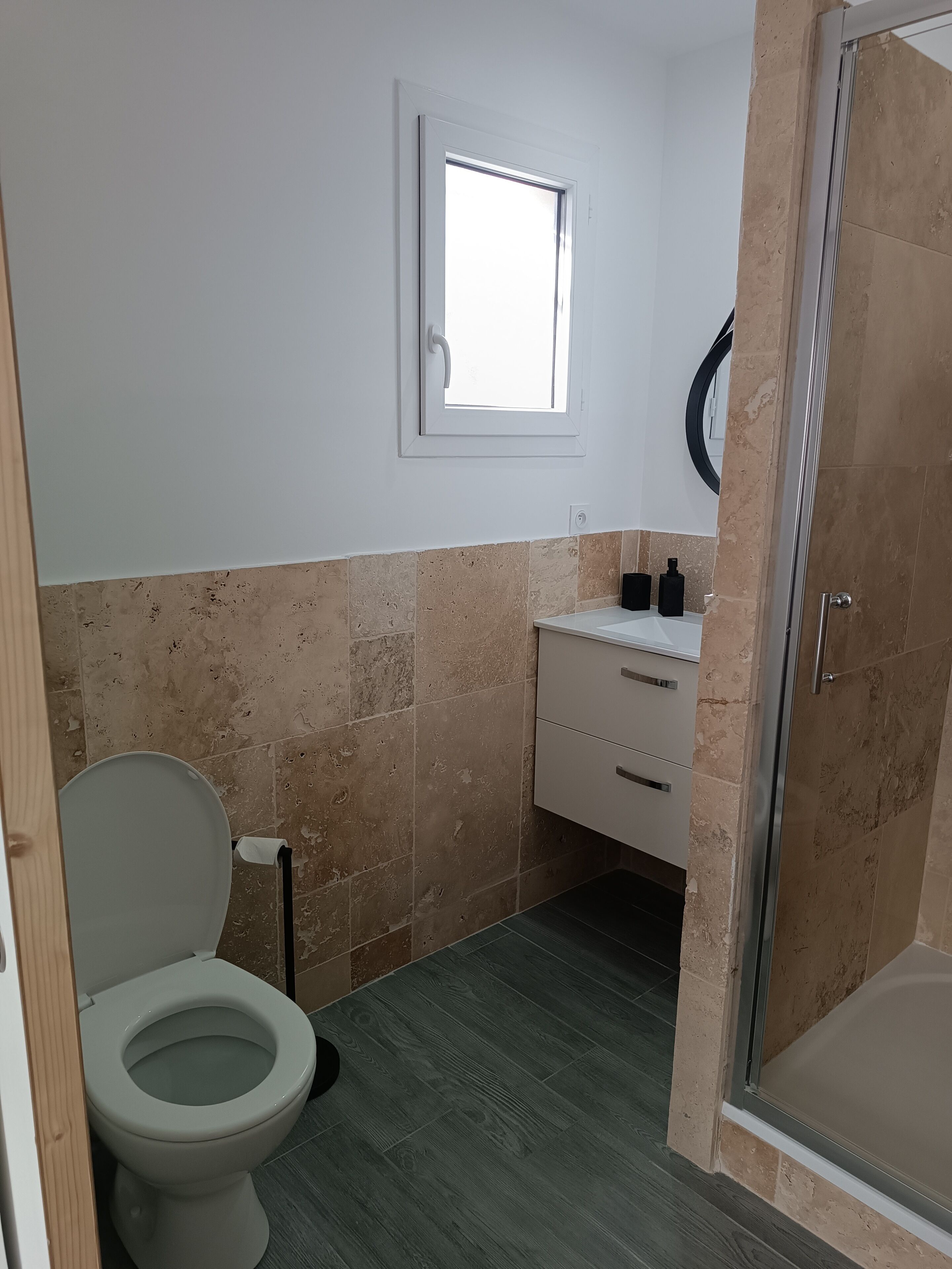 Een badkamer met toilet, wastafel, spiegel en douche.