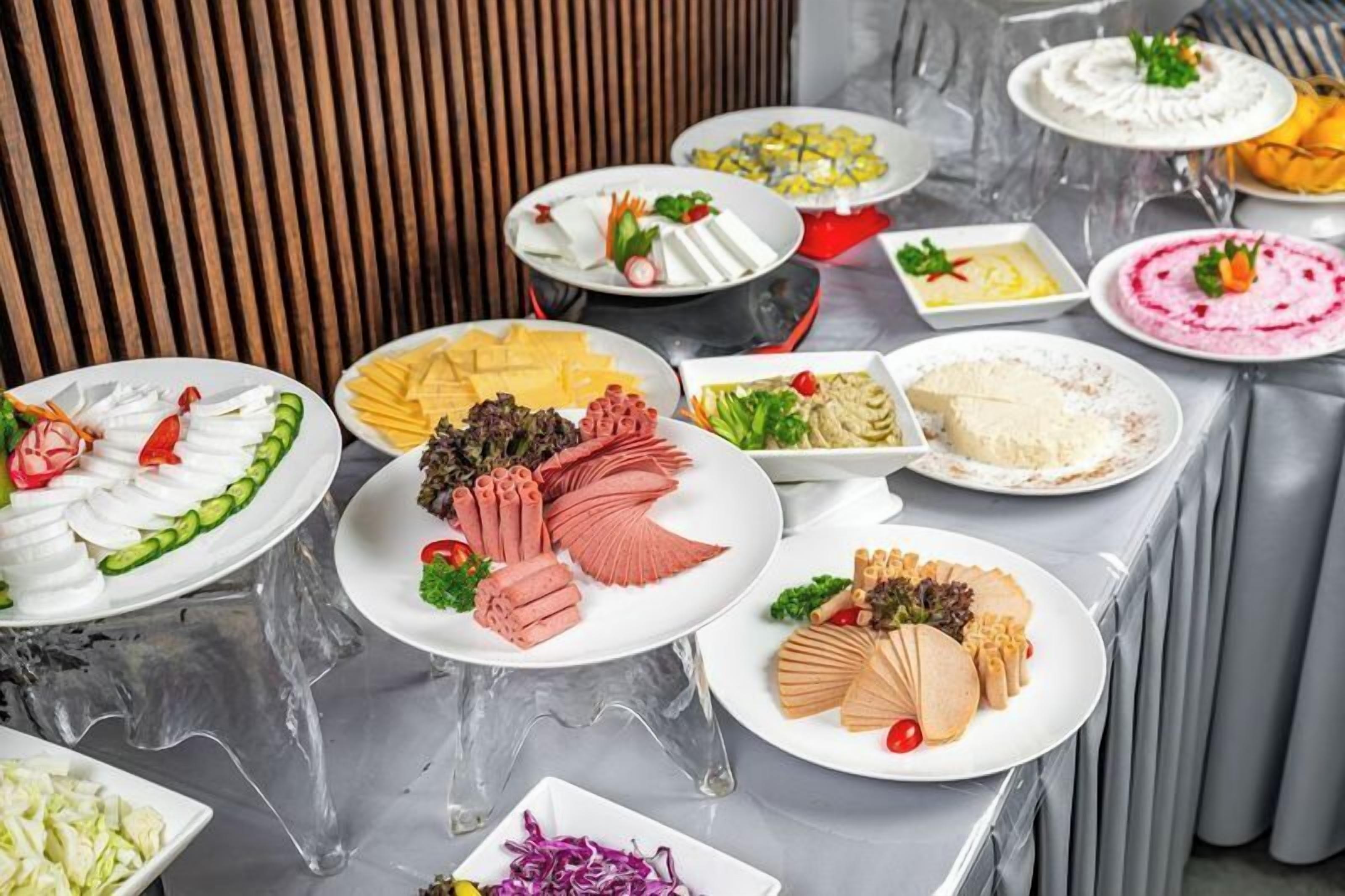 A buffet table with various dishes including meats, cheeses, and salads.