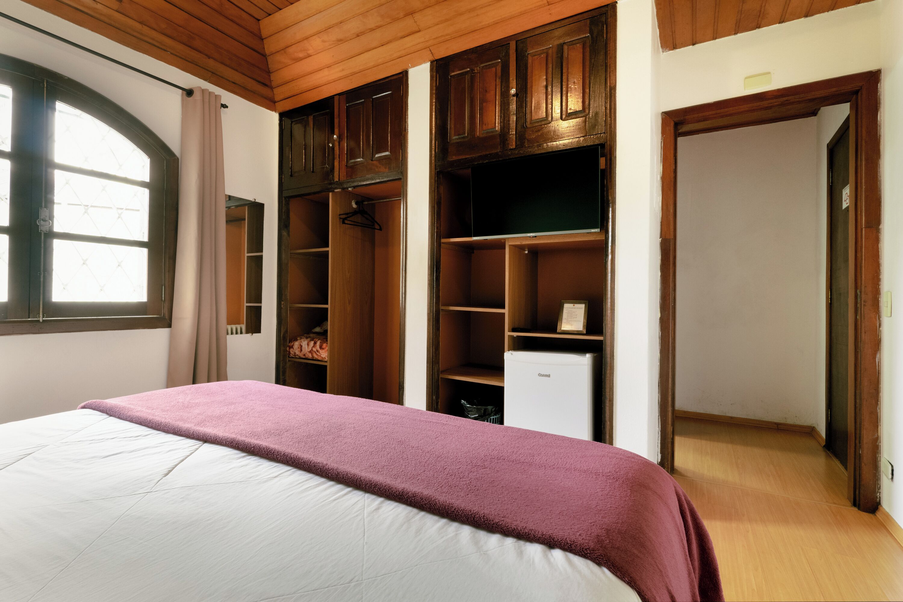 Een slaapkamer met een bed, een kledingkast en een kleine koelkast.