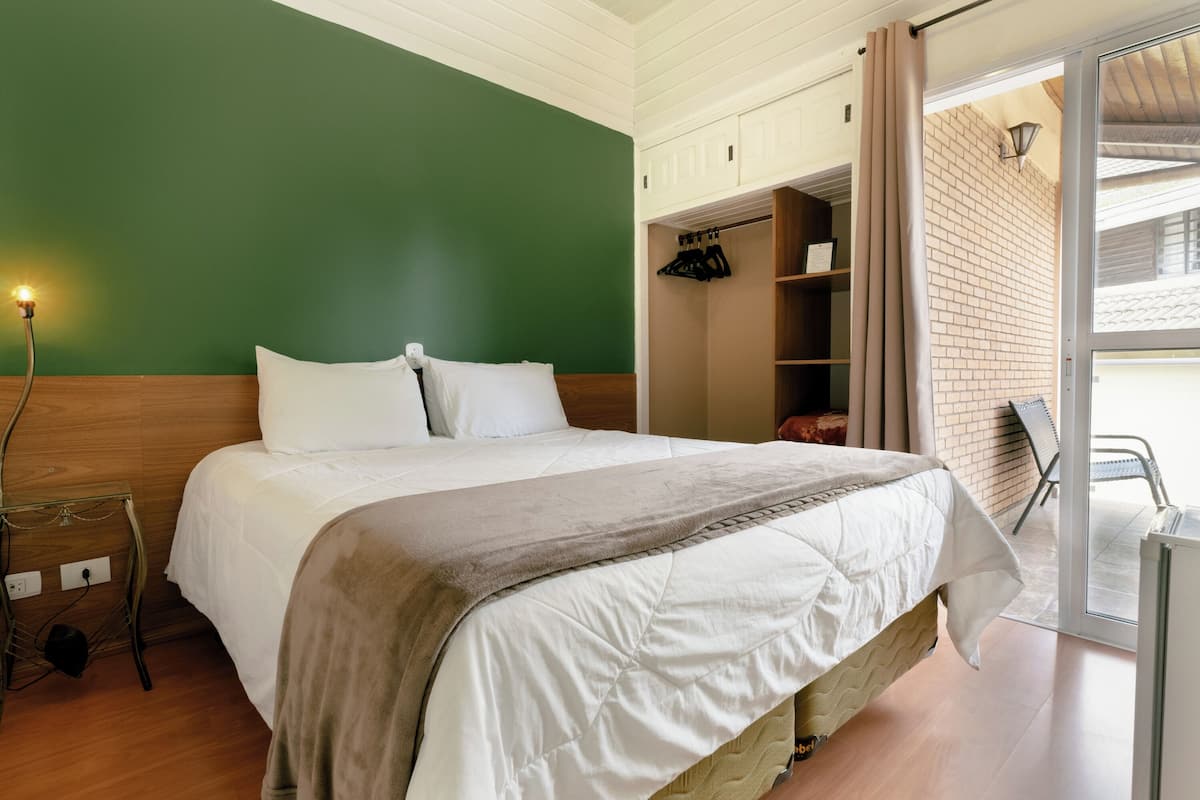 Un dormitorio con cama, armario y puerta corrediza de vidrio a un balcón.