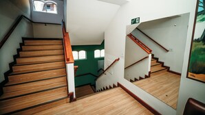 A wooden staircase with a handrail, a green wall, and a small window at the top.
