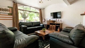 A living room with a black leather sofa, a wooden coffee table, and a flat-screen TV mounted on the wall.