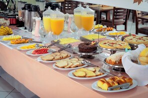 A buffet with various food items and beverages. - Hotel Geneve - 2km do Capivari (Campos do Jordão)