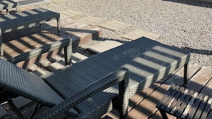 Un patio al aire libre con mobiliario de mimbre y vistas a montañas.