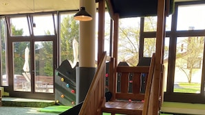 Una escalera de madera con un descansillo cubierto de moqueta verde, ventanas amplias y vistas al exterior.