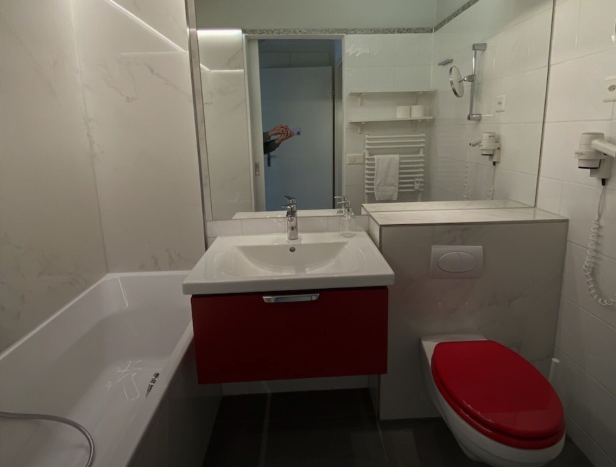 Une salle de bain avec un lavabo blanc, un meuble rouge et des toilettes rouges.