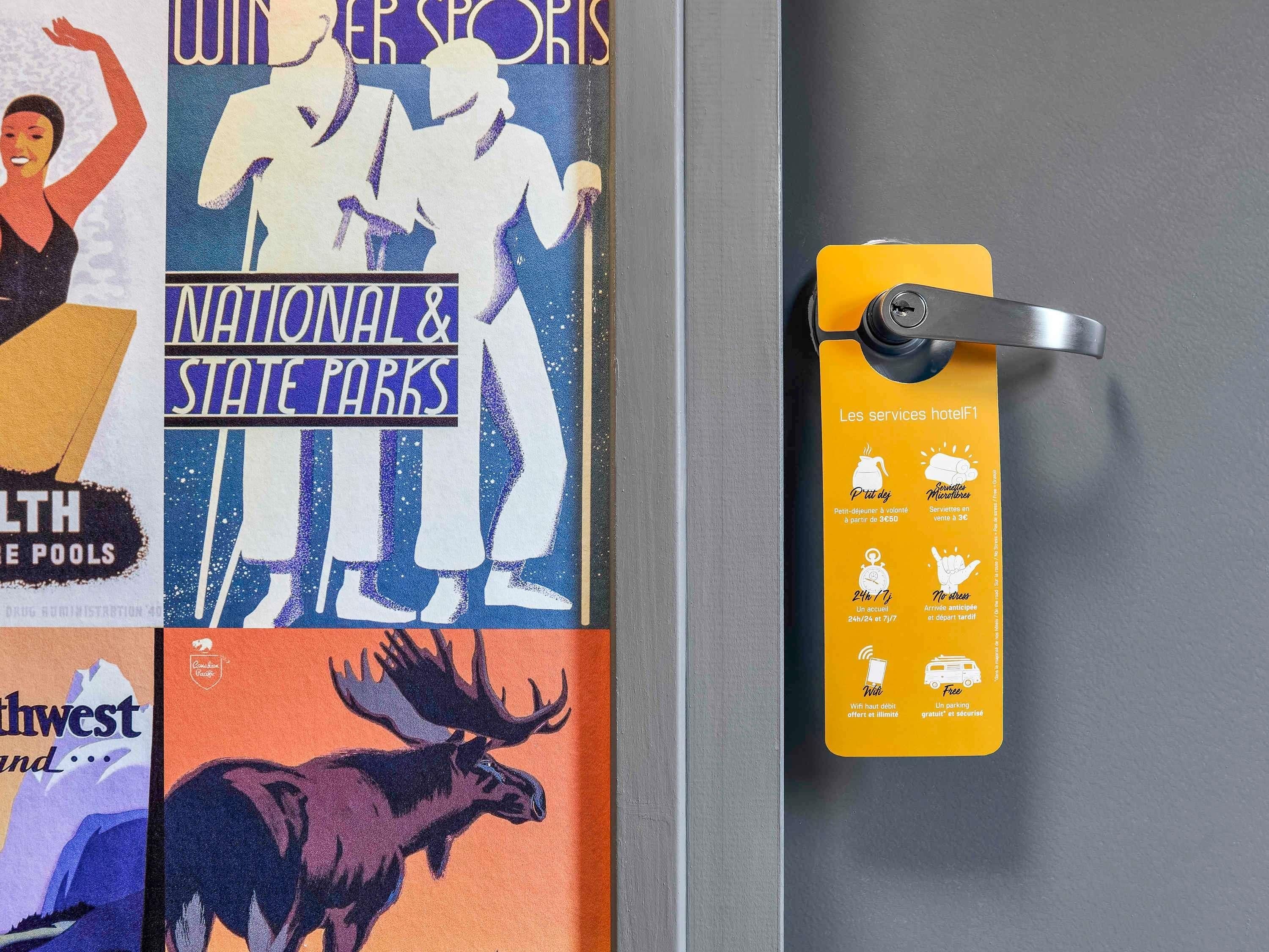 Paret amb cartells publicitaris d'esports i parcs nacionals, i un senyal groc que descriu serveis de l'hotel.